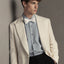 Man wearing a light-colored suit with a white bow tie against a neutral background