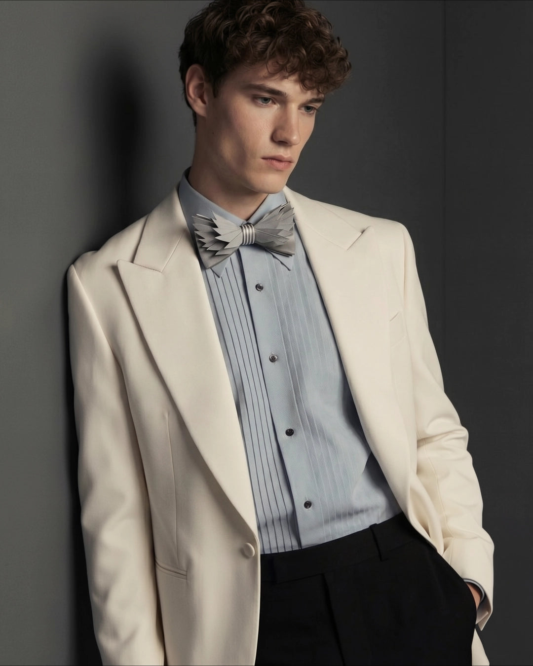 Man wearing a light-colored suit with a blue shirt and bow tie against a gray background